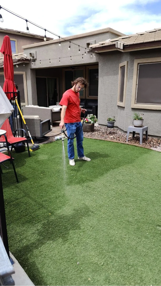 A person applying a yard treatment to artificial turf